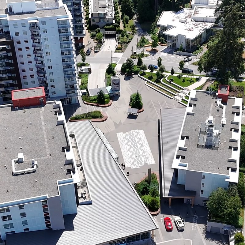 Aerial view of leləm̓ plaza, the central gathering place in the heart of the community