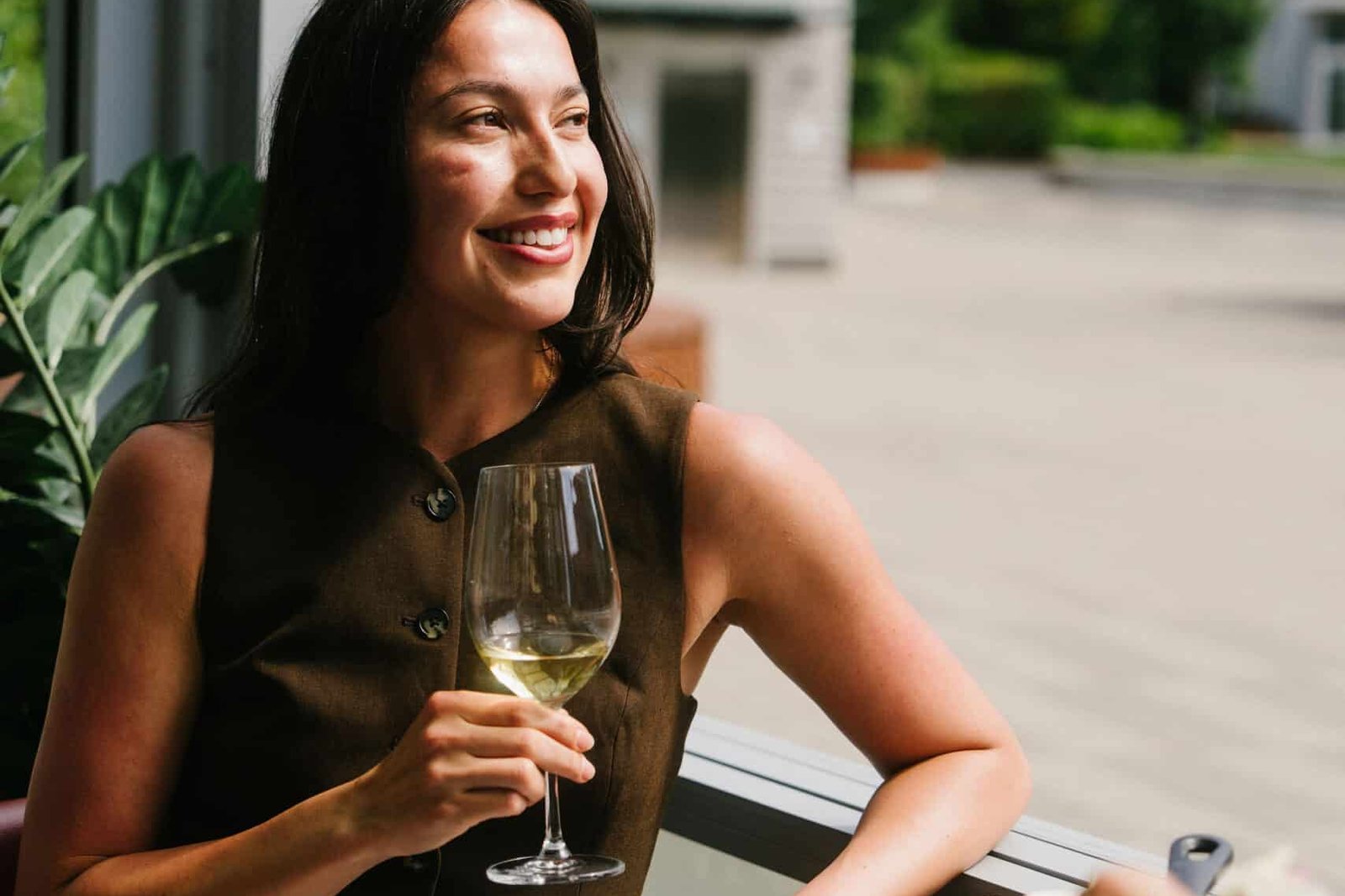 Woman smiling with a glass of wine at leləm̓ village